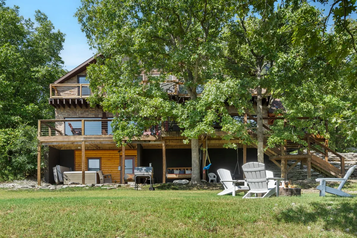This image captures the spacious wooden deck and the large lawn in front of the house, with comfortable seating areas inviting families to relax. The view shows ample outdoor space perfect for games, gatherings, and playtime, with the home as a welcoming backdrop.