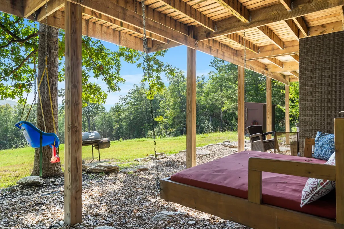 A swing and swing bed are set on an open green lawn, shaded by trees, with a grill visible nearby. The space encourages playful activities, outdoor meals, and relaxed moments, inviting both kids and adults to reconnect with nature and each other.